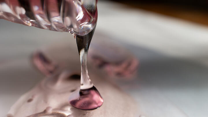A clear gel-like skincare product, pouring out of a container 